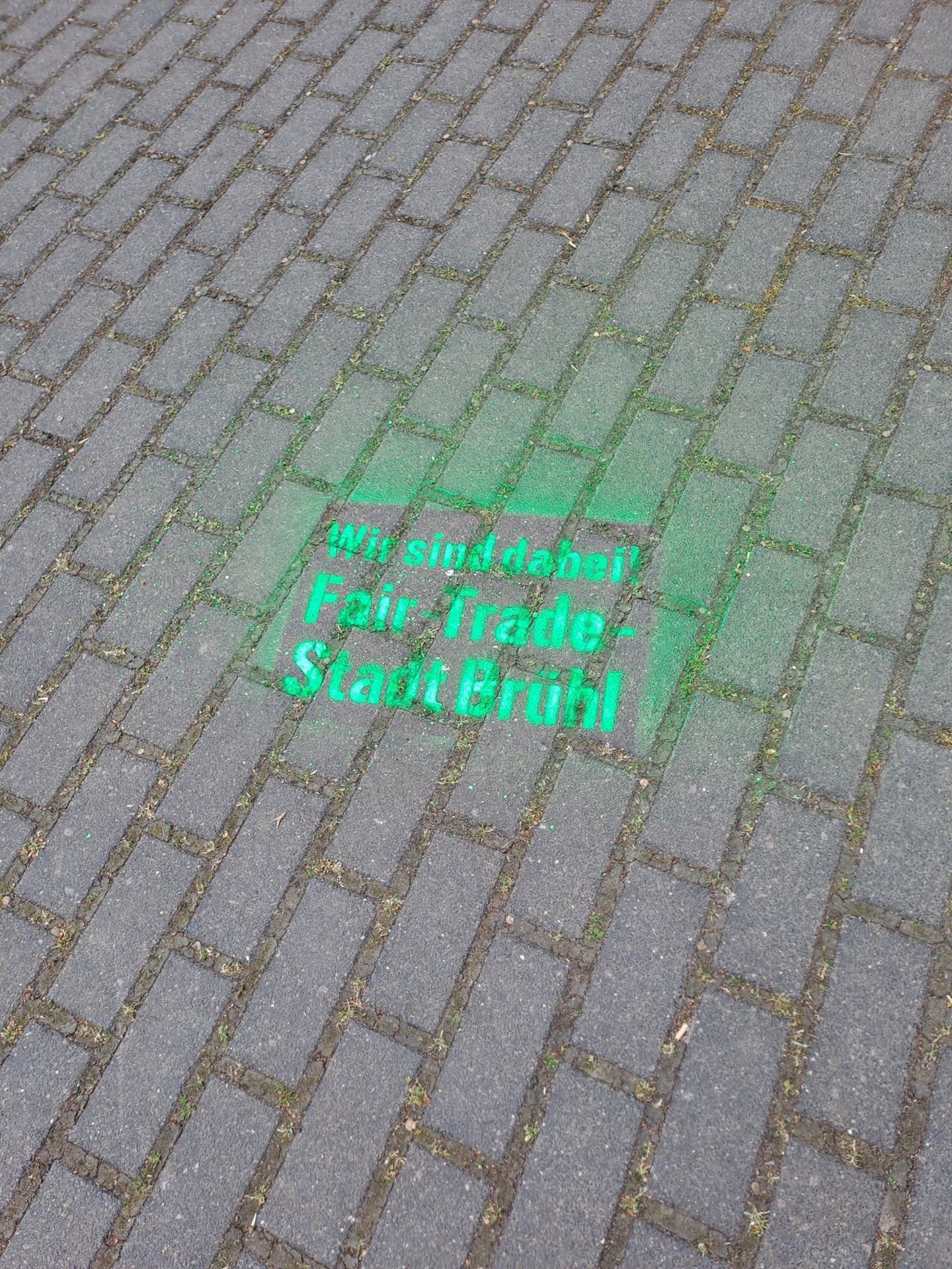 Grüner Fair Trade Schriftzug auf der Straße